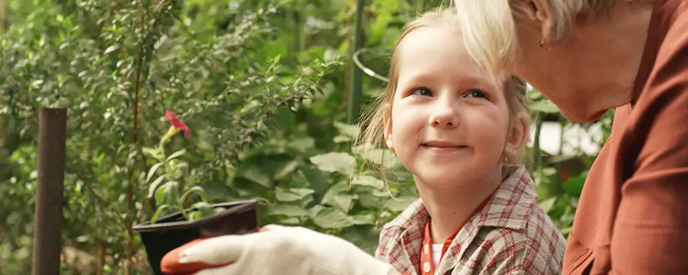 Äldre kvinna med ung flicka planterar en blomma